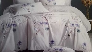 Ein Bett mit weißer Daunendecke und blumigem Bettzeug.