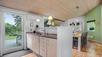 A modern kitchen with a large island, wooden ceiling, and a dining area with a table and chairs.
