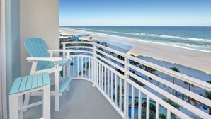 Een balkon met twee lichtblauwe Adirondack-stoelen, een zwembad en uitzicht op het strand.