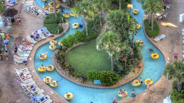 Luchtbeeld van een resort met een groot centraal zwembad, meerdere kleinere zwembaden en diverse glijbanen en tubing zones.