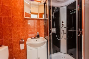 A modern bathroom with a glass-enclosed shower, a white sink, and a marble-tiled wall. - Lovely 1-bed Apartment With Patio in Kastel Stari (Kastela)