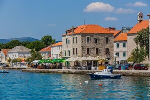A coastal town with stone buildings, a marina, and outdoor seating areas. - Lovely 1-bed Apartment With Patio in Kastel Stari (Kastela)