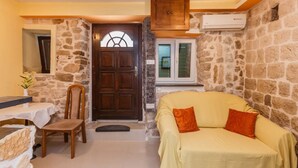 Une pièce chaleureuse avec un mur en pierre, une porte en bois, un canapé jaune et une petite table avec une chaise.