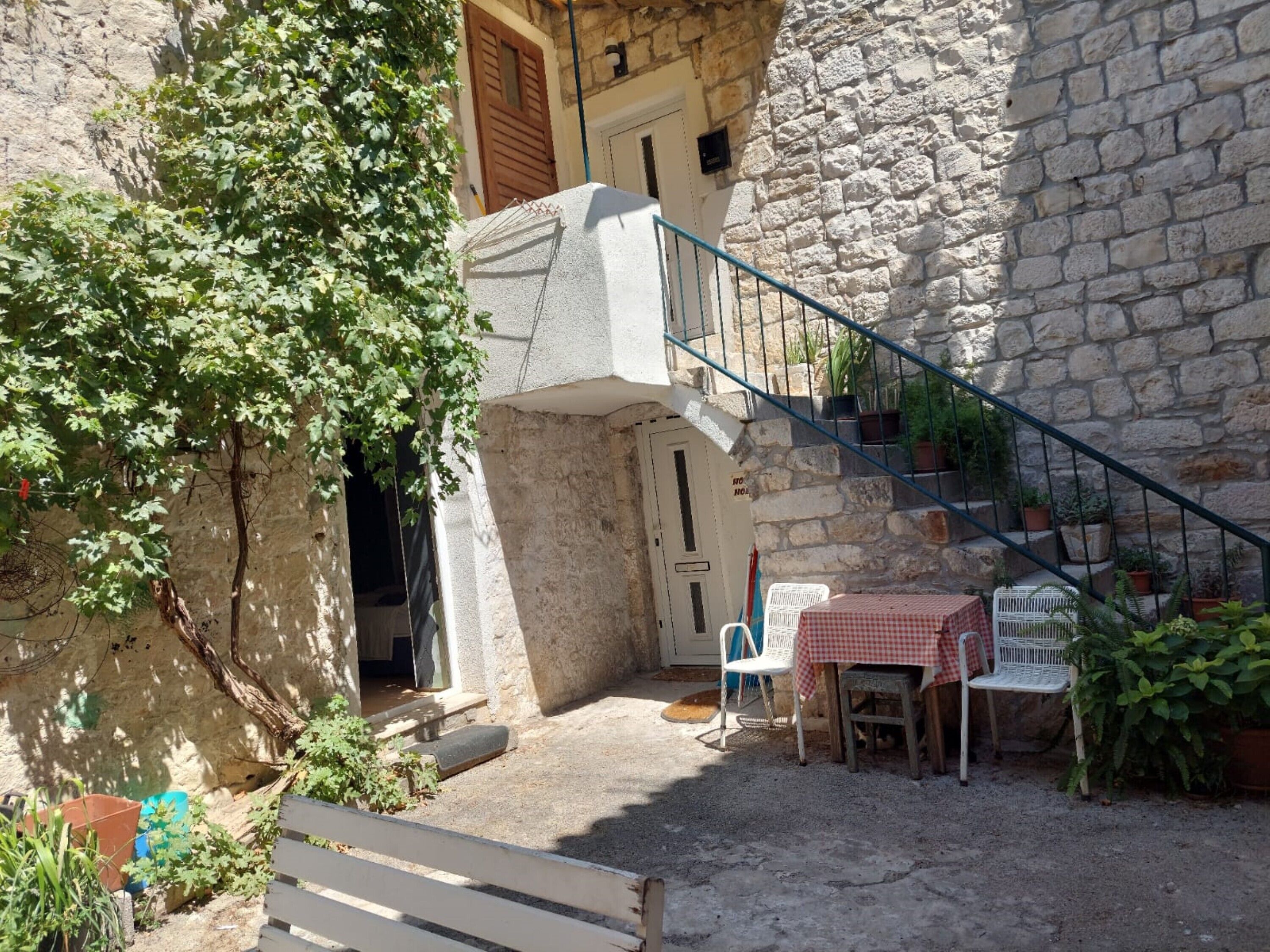 Ein Steinhaus mit Treppe, Tisch und Stühlen sowie Zimmerpflanzen.