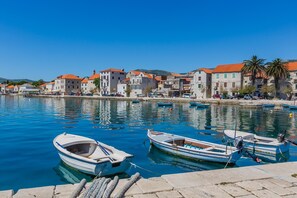 A coastal town with stone buildings, calm water, and boats docked along the shore. - Lovely 1-bed Apartment With Patio in Kastel Stari (Kastela)