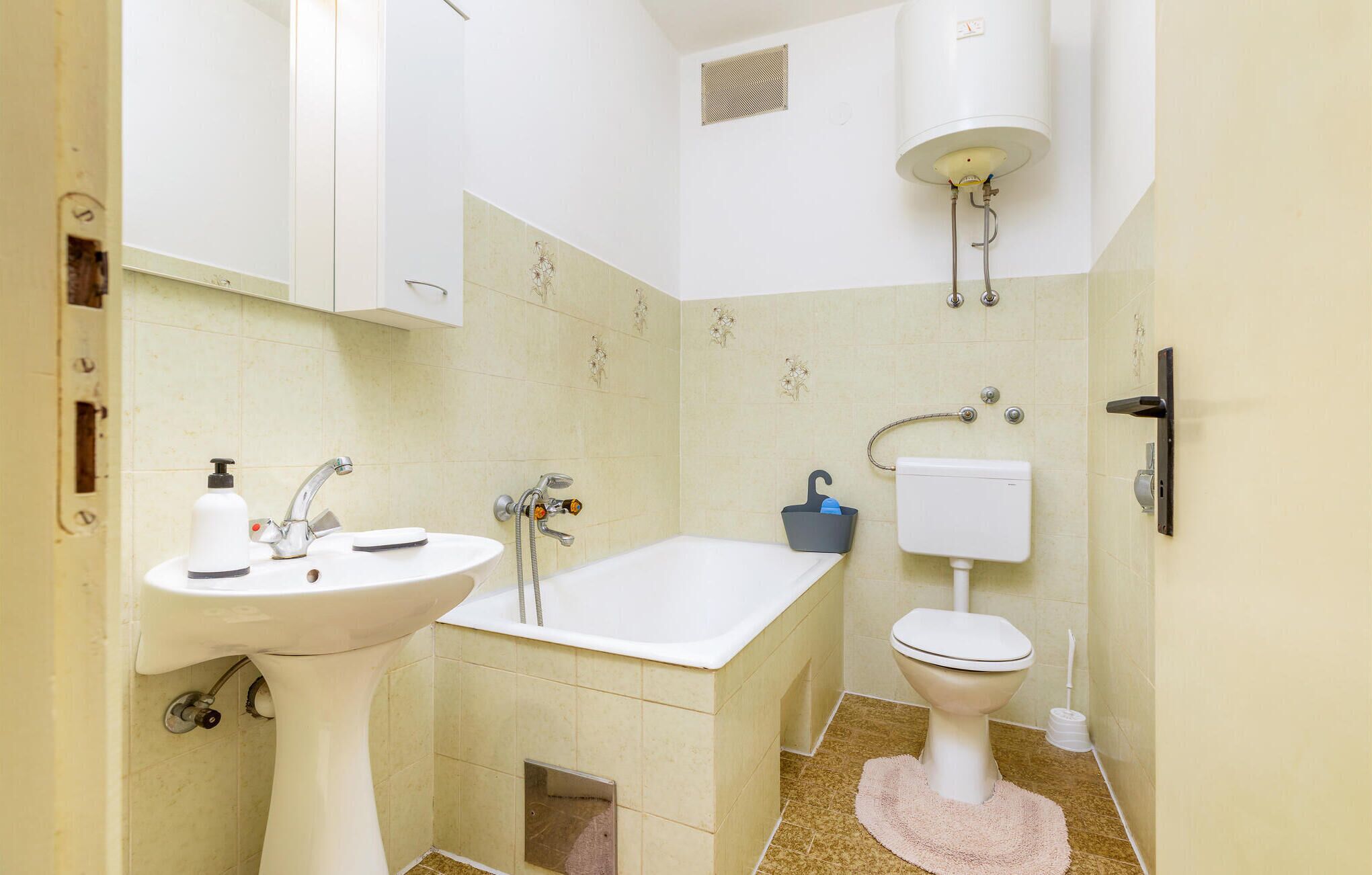 Bagno con lavandino, vasca, water e scaldabagno.