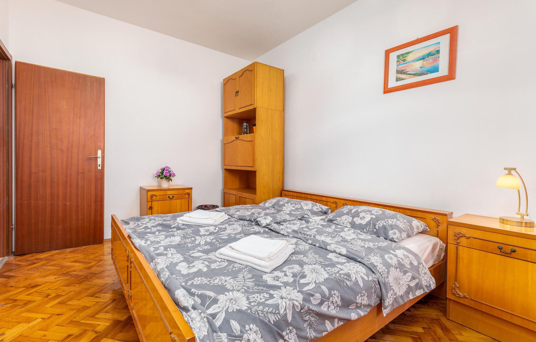 A bedroom with a wooden bed, a nightstand, a wardrobe, and a painting on the wall.