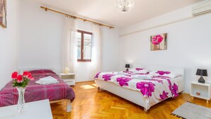 Una camera da letto con due letti, una finestra, un lampadario e un quadro appeso al muro.