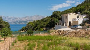A coastal house with a view of the sea and mountains.