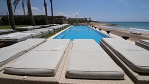 A pool area with lounge chairs and a view of the beach. - LOST AT SEA (Damour)