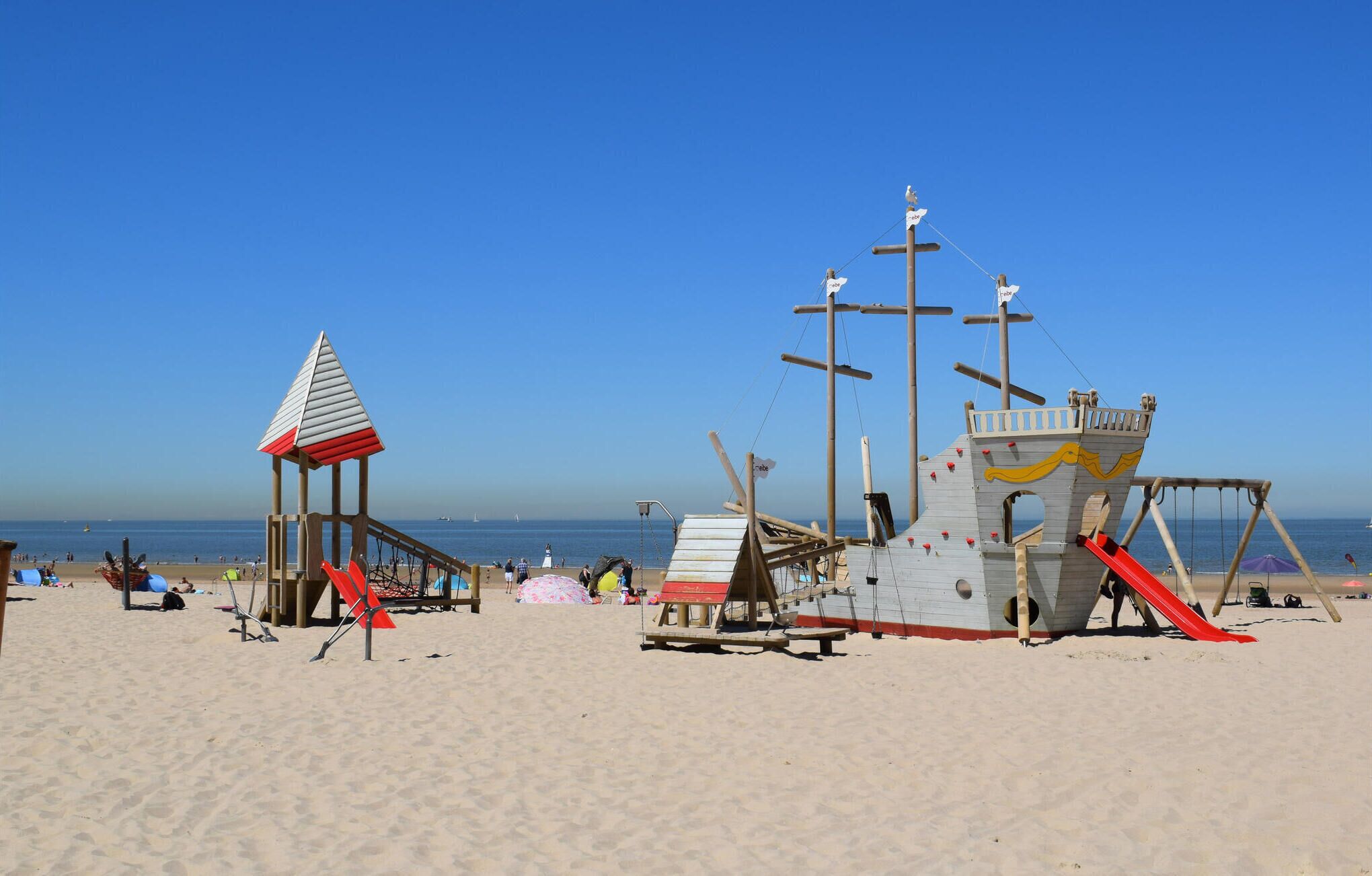 Ein Strand mit einem Rettungsturm und einer Spielkonstruktion.
