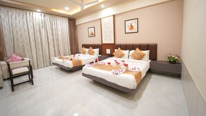 A hotel room with two beds, a sofa, a chair, and a ceiling fan. - The Sky Imperial  Hotel Gopal Darshan (Nathdwara)