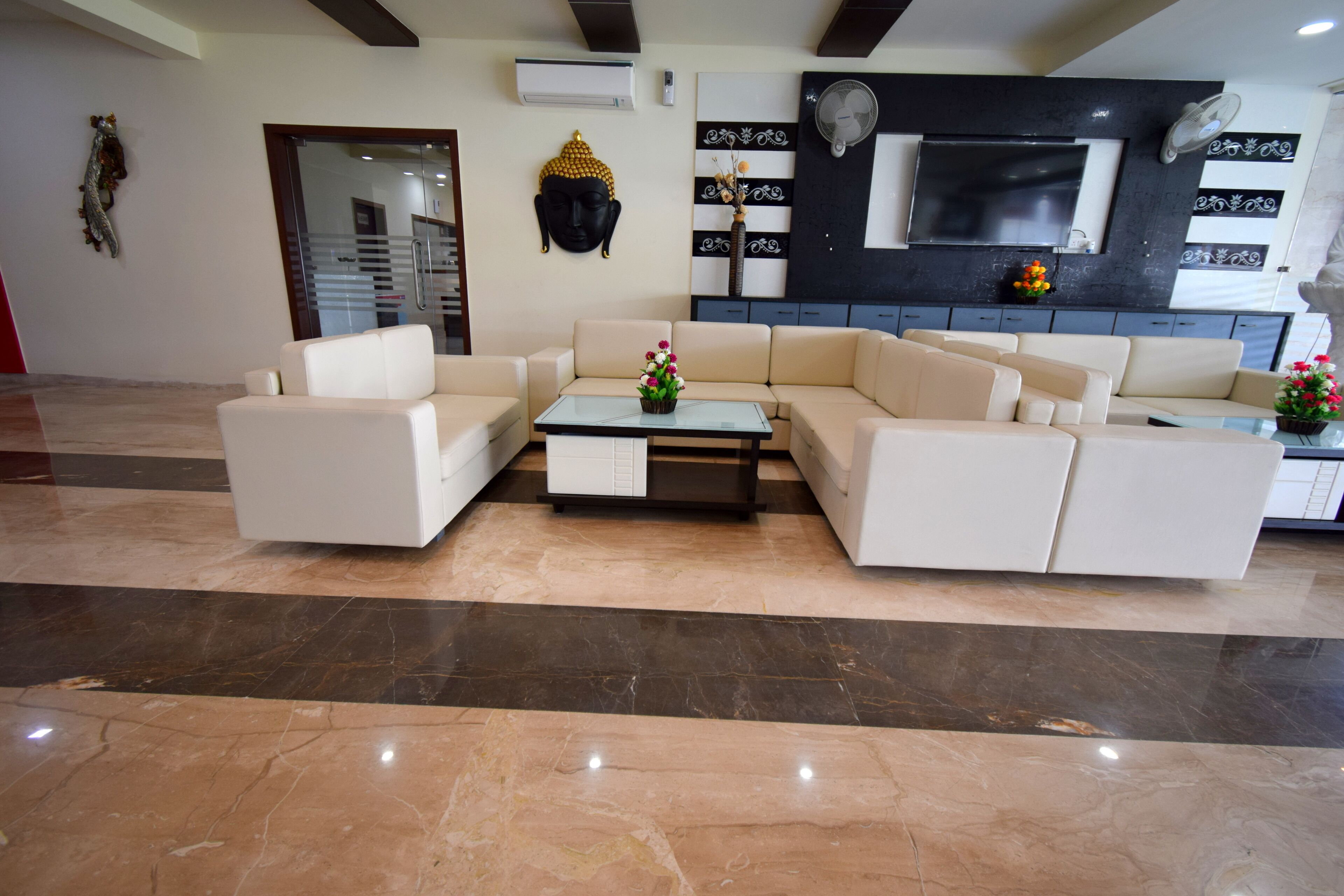 A modern living room with a beige sofa set, a glass coffee table, and decorative items.