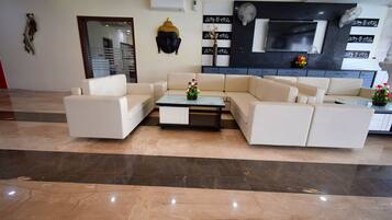 A modern living room with a beige sofa set, a glass coffee table, and decorative items.