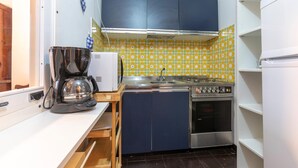 Une cuisine compacte équipée d’une machine à café, d’une cuisinière et d’un réfrigérateur.