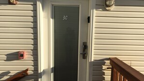 Une porte d’entrée avec une plaque de numéro, un détecteur d’incendie et un système de verrouillage à clavier.