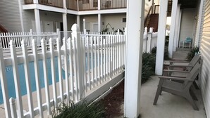 Un espace piscine agrémenté d’une clôture blanche, de chaises longues et d’un patio couvert.