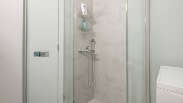 A glass-enclosed shower with a handheld showerhead and a wall-mounted faucet.