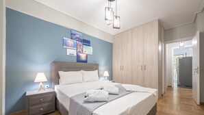 Une chambre à coucher comprenant un lit, des tables de chevet, une armoire et un mur décoré de tableaux.