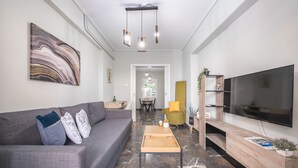 Un salon moderne avec un canapé gris, une table basse en bois, un téléviseur à écran plat et un sol en marbre.