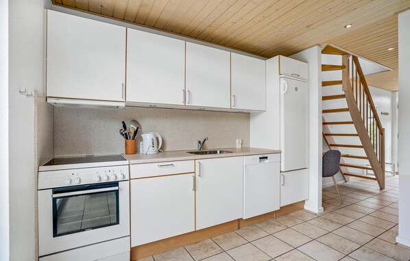 Kitchen with oven, sink, and refrigerator, featuring a speckled backsplash and tiled floor.