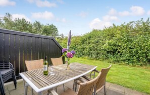 Relax in a serene outdoor space with a patio, complete with a table, chairs, and beautiful flowers.