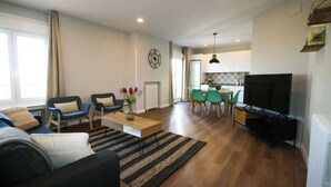 A modern living room with a sofa, chairs, a coffee table, and a TV. - Gran Vía Terrace w/ Royal Palace Views, Central (Madrid)