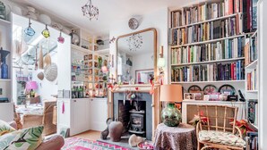 Un salon chaleureux avec une cheminée, des étagères à livres et divers objets de décoration.