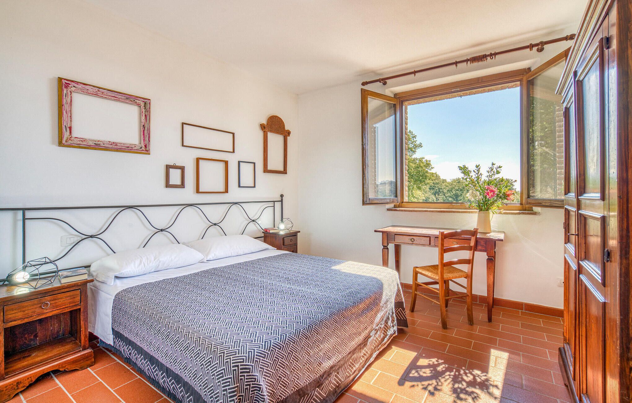 Un dormitorio con cama, mesitas de noche, un escritorio y ventana con vistas.