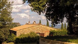 Un edificio de piedra con techo de tejas, rodeado de vegetación y árboles.