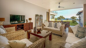 A spacious living room with a television, wicker furniture, and a balcony with a view of the sea. - In 1 word: WOW! Unique, Breathtaking and Luxury! (Candidasa)