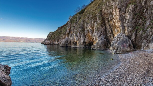 Eine felsige Küste mit klarem Wasser und einer steilen Klippe.