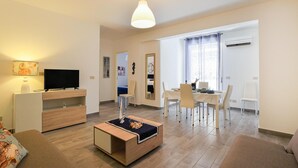 A modern living room with a TV, sofa, coffee table, dining table, and chairs. - 2 bedroom awesome apartment in Trappeto (Trappeto)