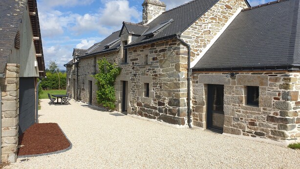 A stone building with a gravel driveway and a small table with chairs. - House (Neulliac)