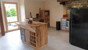 A modern kitchen with a wooden island, built-in appliances, and a stone accent wall. - House (Neulliac)