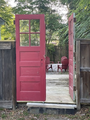A red door leading to a wooden deck with outdoor furniture. - Updated Victorian Red Door Revival in Downton St Aug (Saint Augustine)