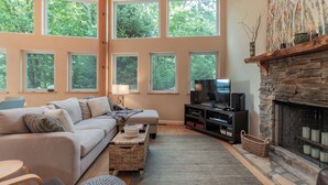 A cozy living room with a fireplace, large windows, a sofa, and a TV. - Moonlight Ridge*Sleeps 8*PetsoK*VIEW*Resort Access (Deep Gap)