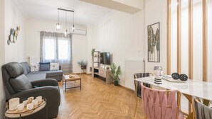 A modern living room with a sofa, a dining table, and a TV. - Elegant Suite by CloudKeys (Athens)