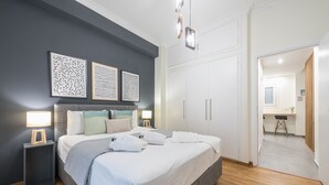 A modern bedroom with a large bed, bedside tables, and artwork on the wall. - Elegant Suite by CloudKeys (Athens)