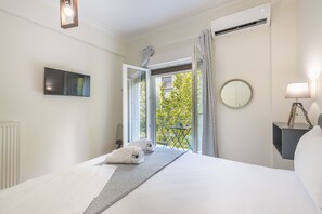 A hotel room with a bed, a TV, a balcony with a view, and a lamp.