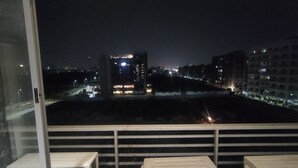 Vista nocturna desde una ventana con una vista panorámica de la ciudad, incluyendo edificios y una fuente de luz distante.
