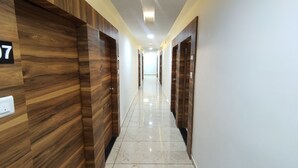 Un pasillo de hotel con paneles de madera, puertas numeradas y un suelo de baldosas brillantes.