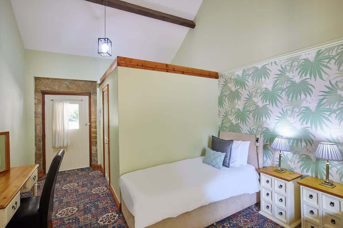 A bedroom with a bed, bedside tables, a desk, and a chair.