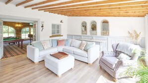 Un salon spacieux avec un canapé blanc, un fauteuil gris et un plafond en bois.