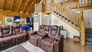 Amplia sala de estar con un sofá de cuero grande y una escalera de madera que conduce a un nivel superior.