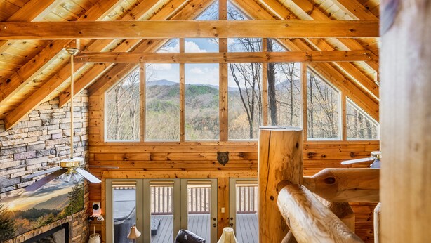 Una cabaña de madera con techo alto, ventanas amplias y vista al bosque circundante.