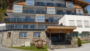 Ein mehrstöckiges Hotel mit Balkonen, einer steinernen Fassade und einem Holzeingang.