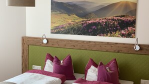 Ein Hotelzimmer mit Bett, grünem Kopfteil und einem Landschaftsbild darüber.