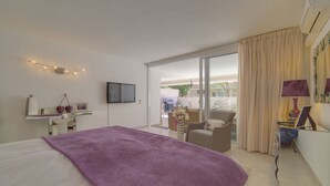 A hotel room with a bed, a desk, a chair, a TV, and a balcony with curtains. - Luxury Apartment, Fast WIFI, Large Terrace, Heated Pool, Marazul (Adeje)