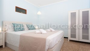 A bedroom with a bed, a nightstand, a wardrobe, and a wall-mounted light fixture. - 3 bedrooms ground floor, large terrace and pool, near the beach. (Can Picafort)